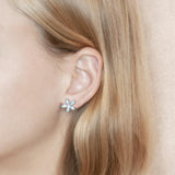 In this photo there is a model wearing a 925 sterling silver pikake flower stud earring with blue larimar gemstones.