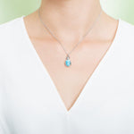 In this photo there is a model with a white shirt wearing a sterling silver pineapple pendant with one blue larimar gemstone.