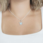 The picture shows a model wearing a 925 sterling silver larimar sea turtle pendant.