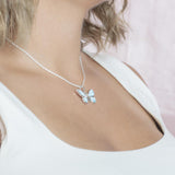 In this photo there is a model turned to the right with blonde hair and a white shirt, wearing a sterling silver butterfly pendant with blue larimar gemstones and aquamarine.