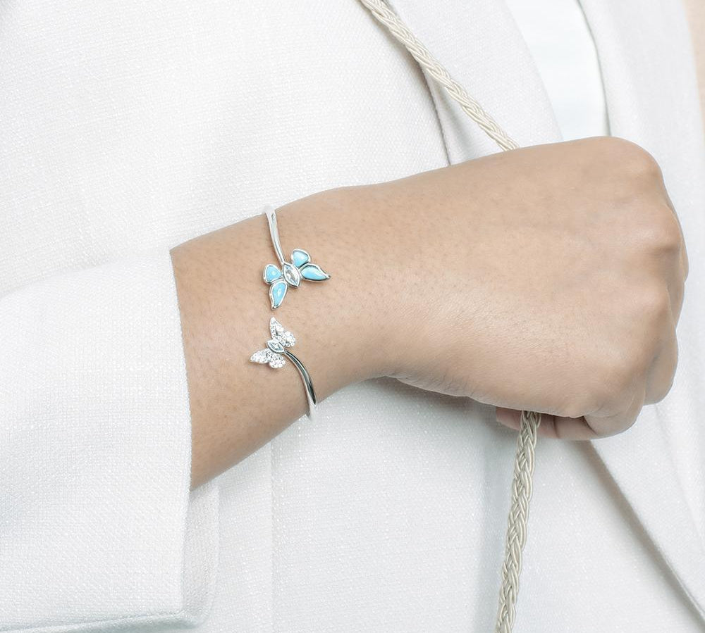 This photo has a model wearing a 925 sterling silver bangle with two butterflies and blue larimar, topaz, and aquamarine gemstones.