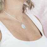 The picture shows a model wearing a 925 sterling silver larimar sand dollar pendant with topaz.