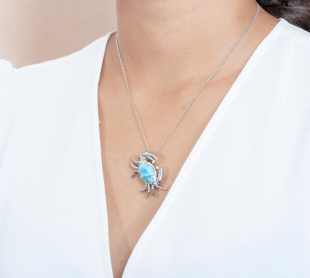 The picture shows a model wearing a 925 sterling silver larimar sand dune blue crab pendant.