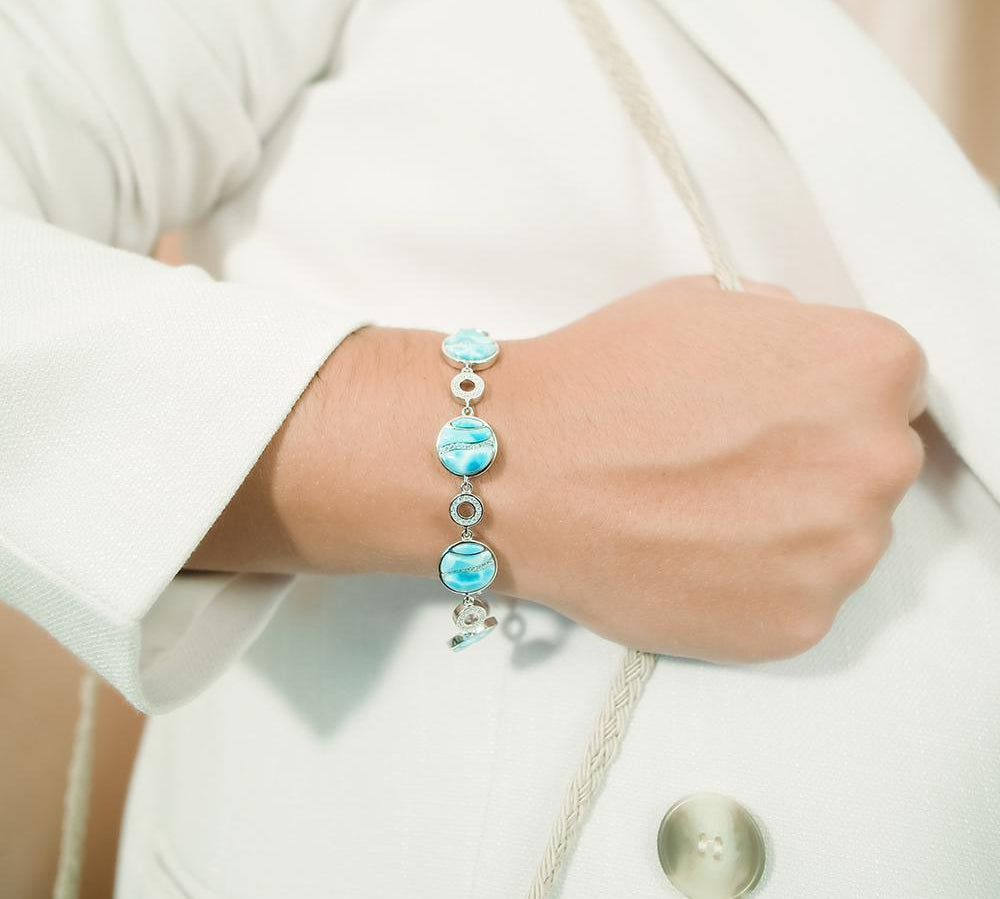The picture shows a model wearing a 925 sterling silver larimar striped circle bracelet with topaz.