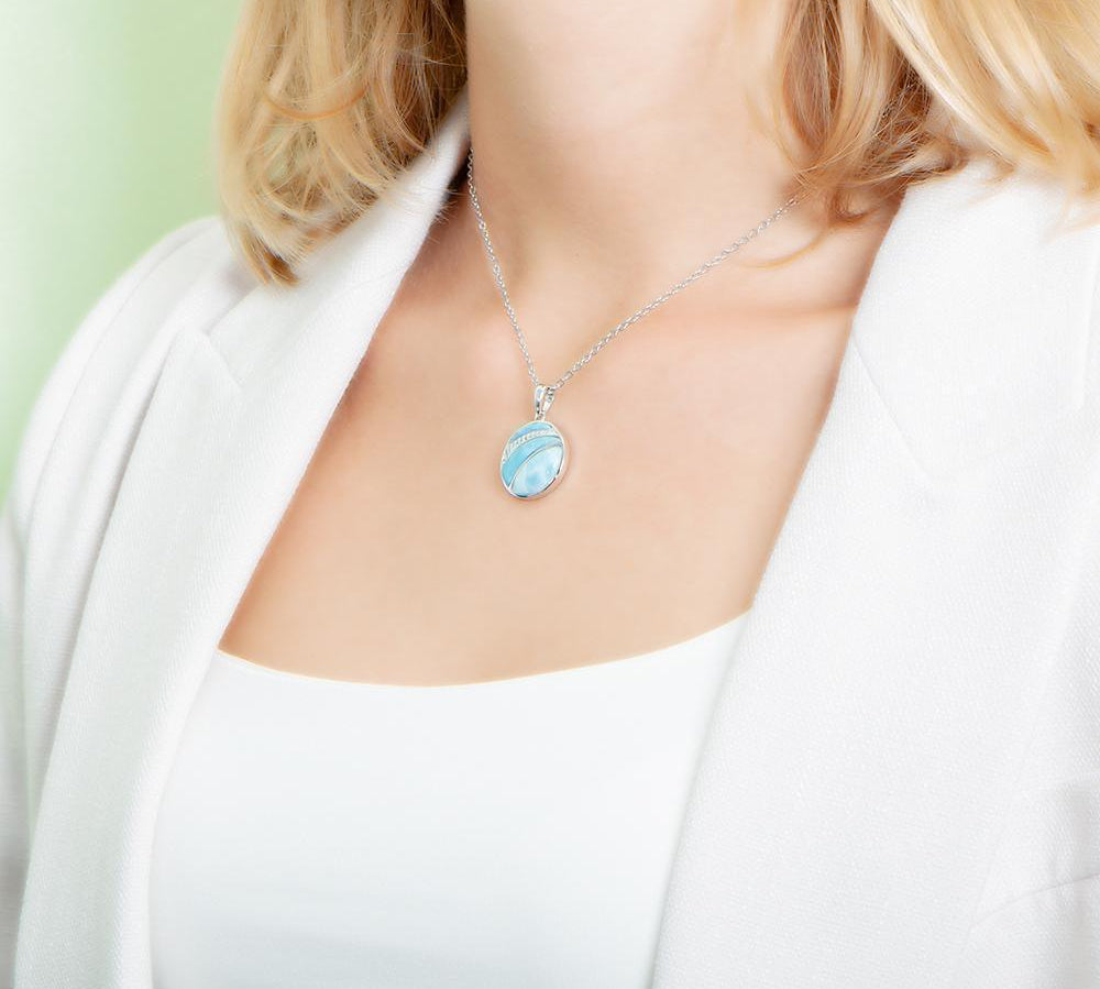 The picture shows a model wearing a 925 sterling silver larimar striped circle pendant with topaz.