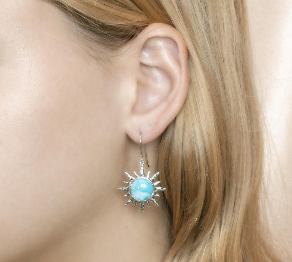 In this photo there is a model wearing a 925 sterling silver sun hook earring with a blue larimar gemstone.