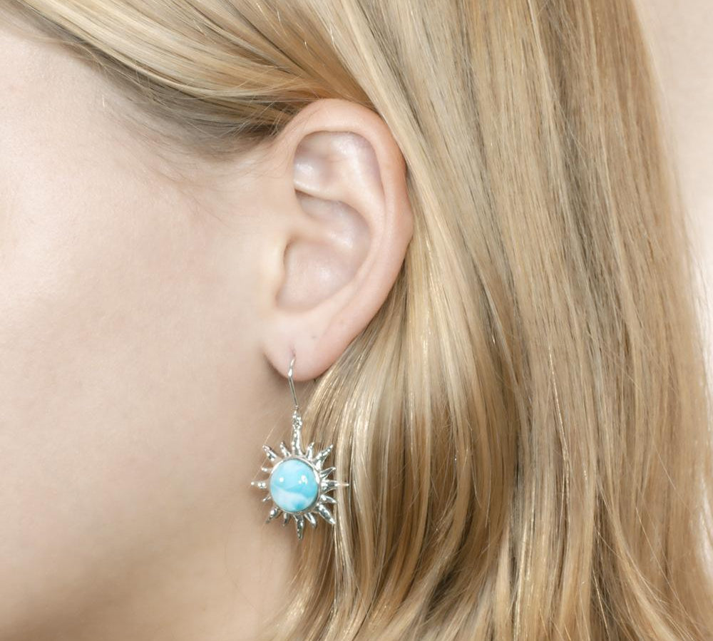 In this photo there is a model wearing a 925 sterling silver sun hook earring with a blue larimar gemstone.