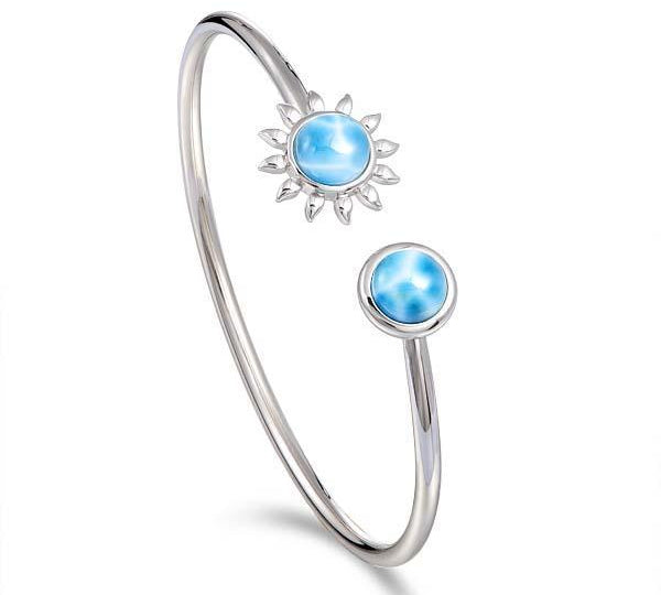 In this photo there is a 925 sterling silver sunflower and circle bangle with two blue larimar gemstones.