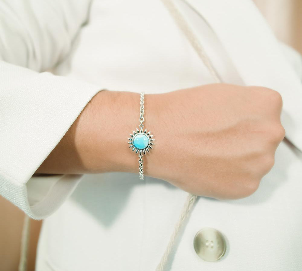 In this photo there is a model wearing a 925 sterling silver sunflower bracelet with one larimar gemstone.