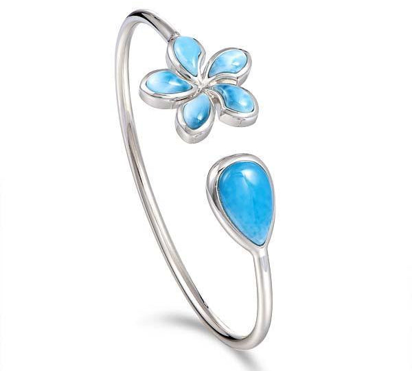 In this photo there is a sterling silver plumeria and teardrop pendant with blue larimar gemstones.
