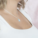 The picture shows a model wearing a 925 sterling silver larimar teardrop pendant.