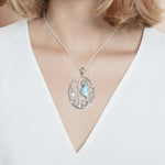 The picture shows a model wearing a 925 sterling silver pendant with a seahorse, starfish, and seaweed including a larimar gemstone and cubic zirconia.
