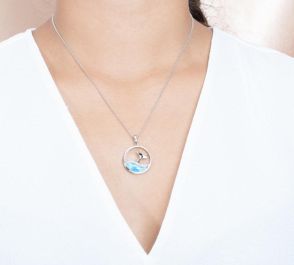 The picture shows a model wearing a 925 sterling silver larimar whale tail wave pendant with topaz.