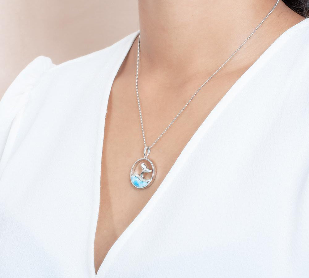 The picture shows a model wearing a 925 sterling silver larimar whale tail wave pendant with cubic zirconia.