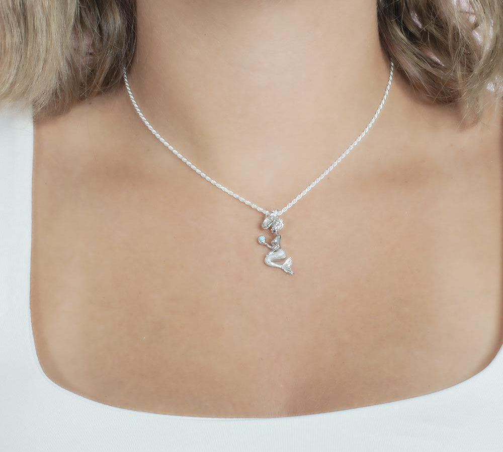 The picture shows a model wearing a small 925 sterling silver larimar wishing mermaid pendant.