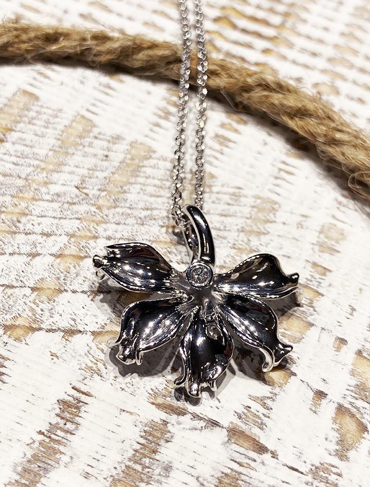 In this photo there is a white gold naupaka flower pendant with one diamond.