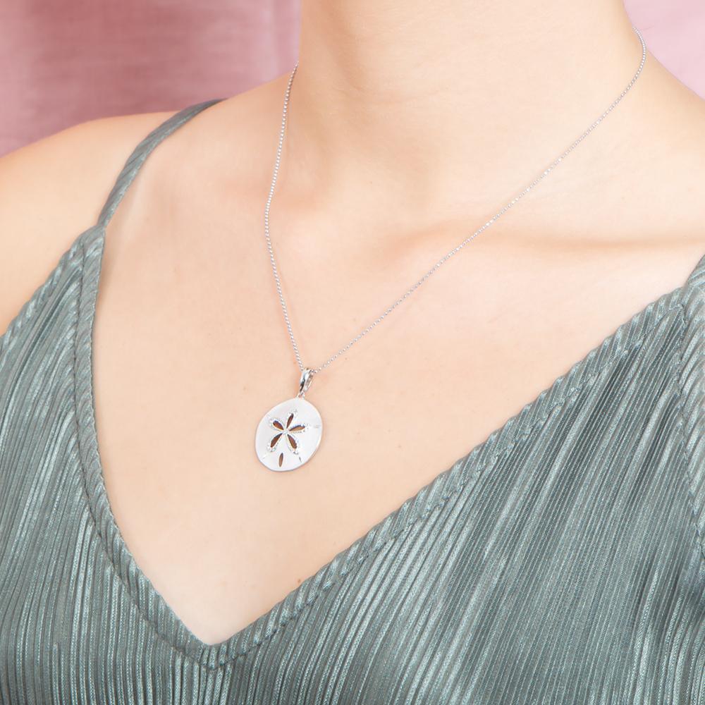 The picture shows a model wearing a 925 sterling silver, white gold plated, sand dollar cut out pendant with topaz.