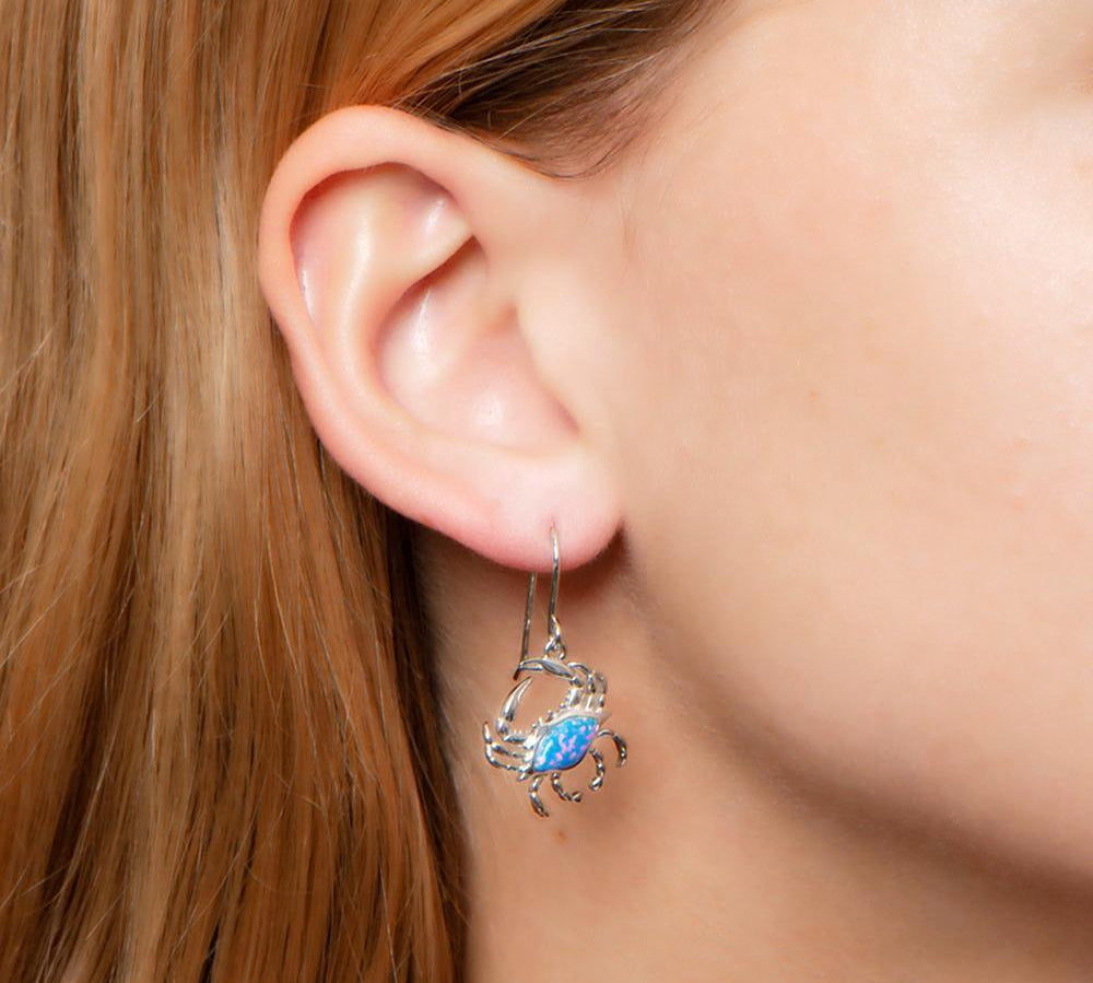 The picture shows a model wearing a 925 sterling silver opalite blue crab earring.