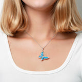 In this photo there is a model with strawberry blonde hair and a white shirt, wearing a sterling silver butterfly pendant with blue opalite gemstones and topaz.