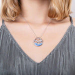 The picture shows a model wearing a 925 sterling silver opalite three jumping dolphins pendant with topaz.