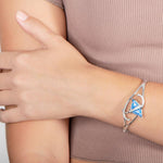 The picture shows a model wearing a 925 sterling silver eagle ray bangle with two opalite gemstones and topaz.