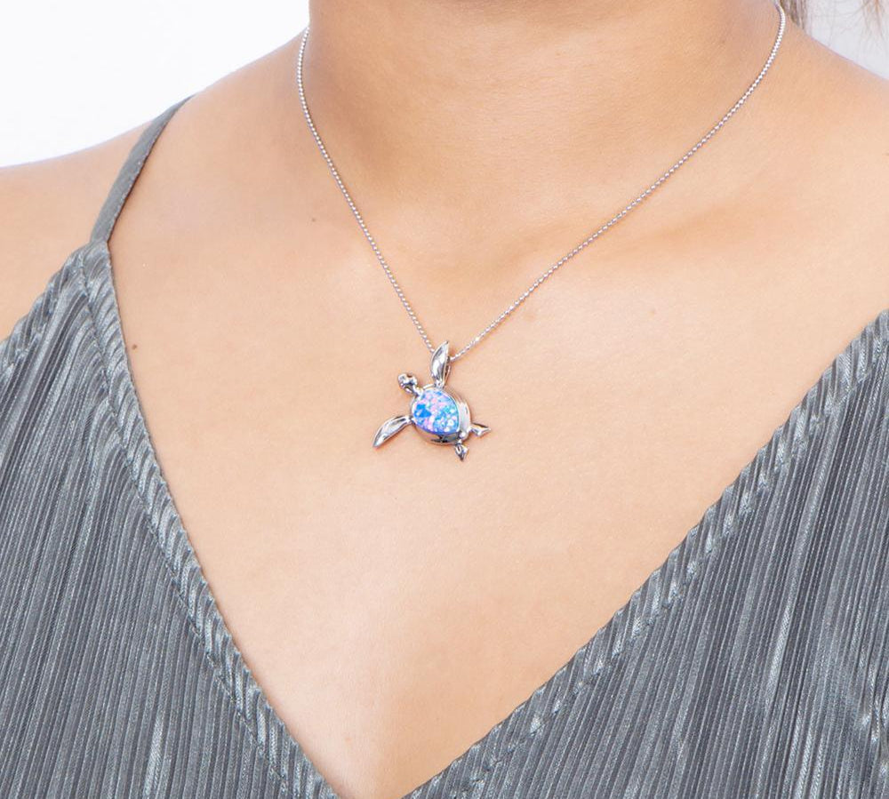 The picture shows a model wearing a 925 sterling silver opalite sea turtle pendant.