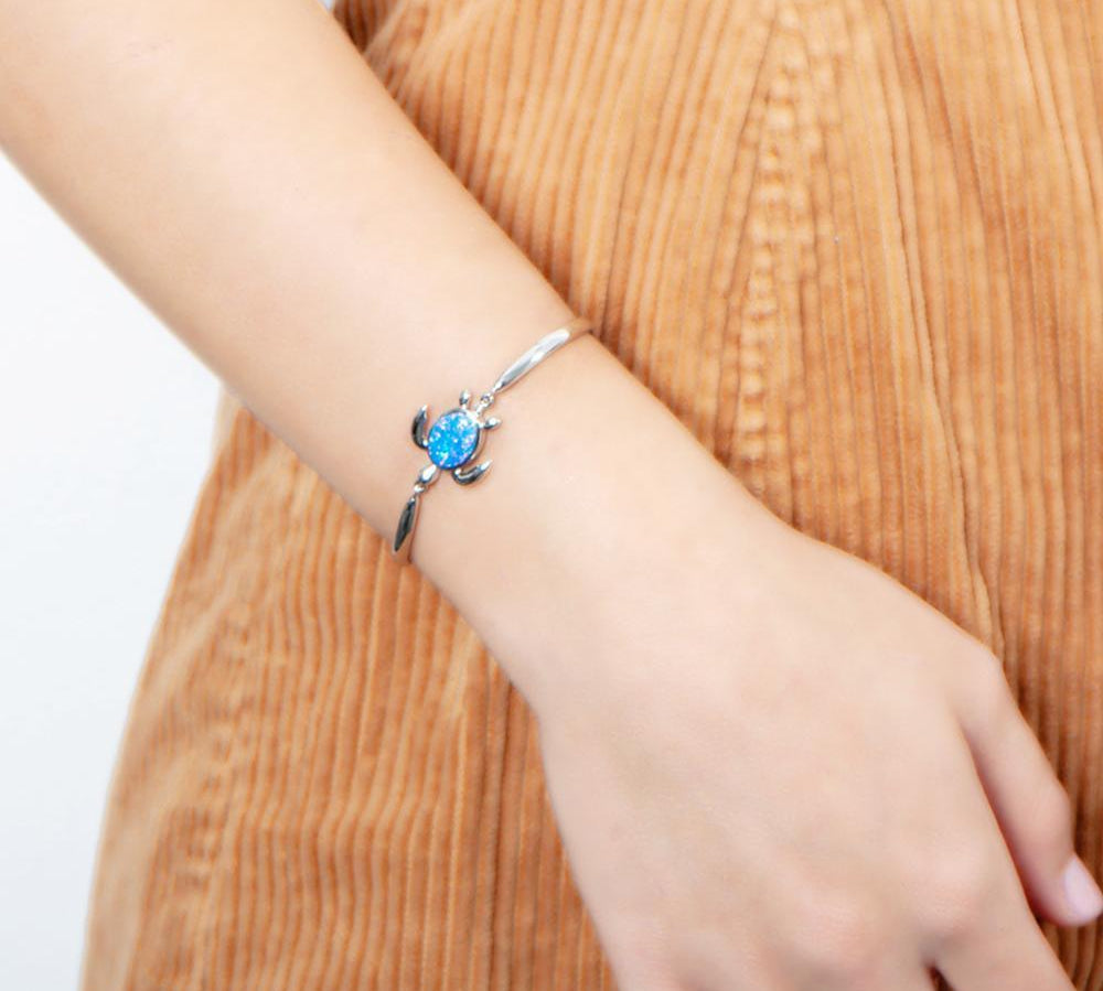 The picture shows a model wearing a 925 sterling silver opalite sea turtle bracelet.