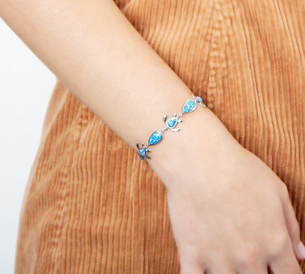 The picture shows a model wearing a 925 sterling silver opalite sea turtle and teardrop charm bracelet