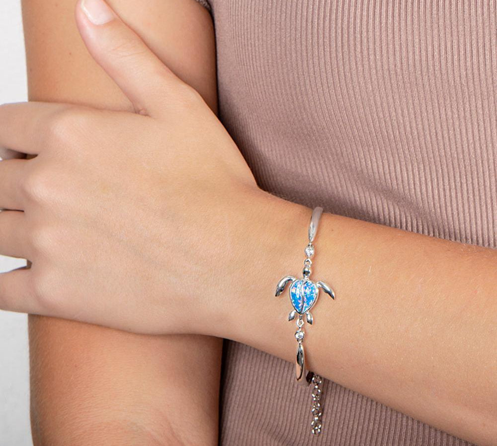 The picture shows a model wearing a 925 sterling silver opalite sea turtle bracelet.