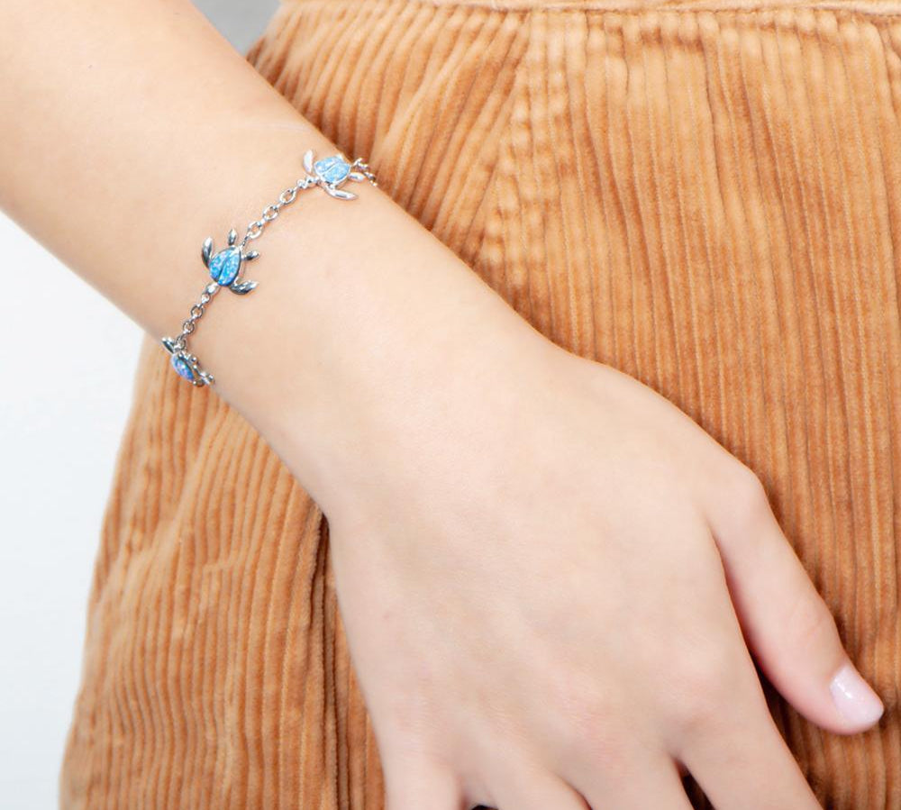 The picture shows a model wearing a 925 sterling silver opalite sea turtle charm bracelet