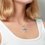 The picture shows a model wearing a 925 sterling silver opalite cross pendant with cubic zirconia.