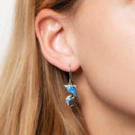 The picture shows a model wearing a 925 sterling silver opalite two dolphin earring.