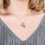 The picture shows a model wearing a 925 sterling silver opalite dolphin through a circle pendant with topaz.