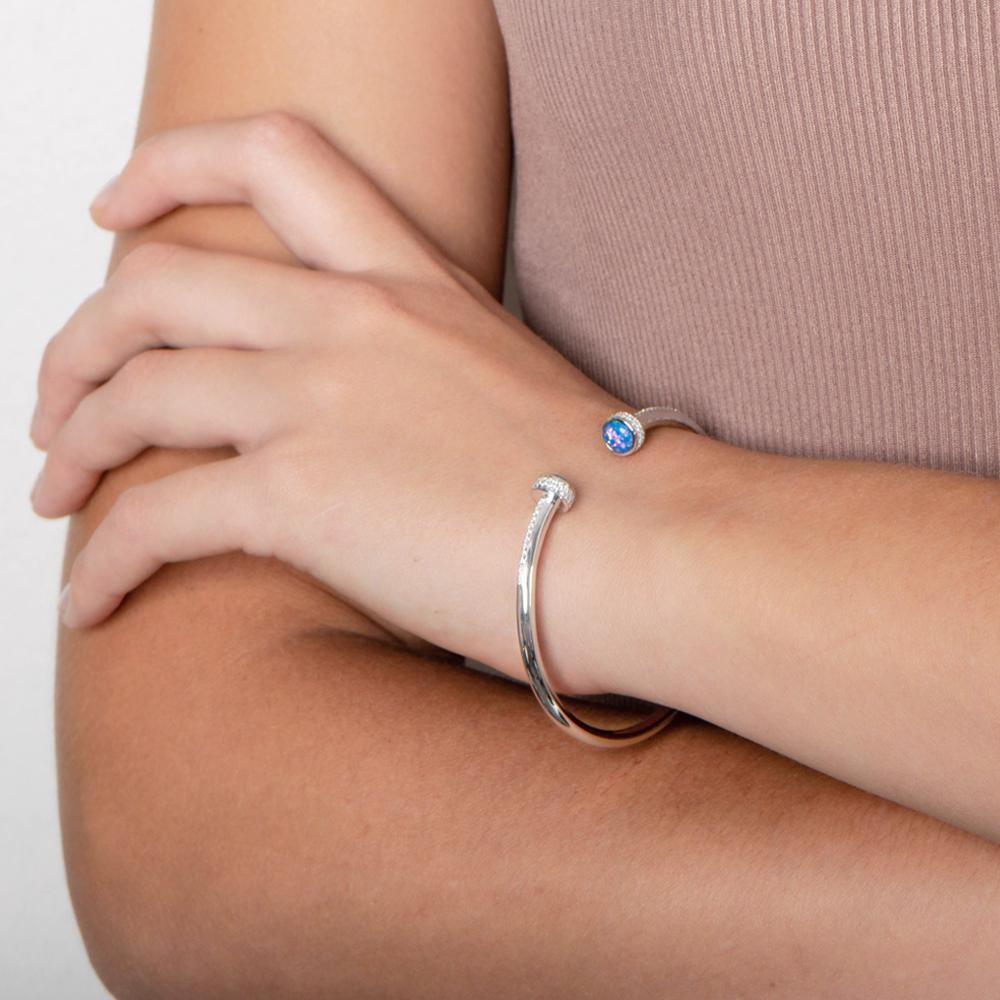 The picture shows a model wearing a 925 sterling silver bangle with two opalite gemstones and topaz.