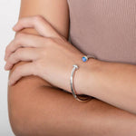 The picture shows a model wearing a 925 sterling silver bangle with two opalite gemstones and topaz.