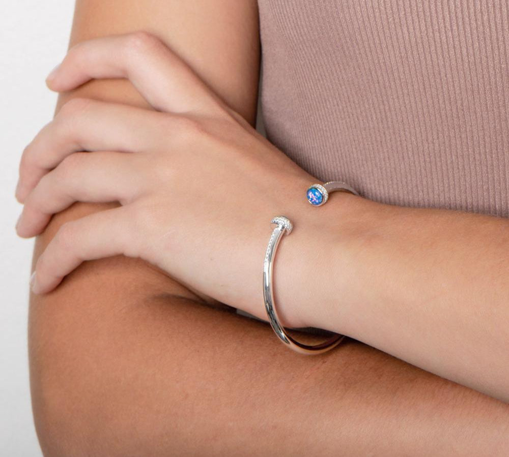 The picture shows a model wearing a 925 sterling silver bangle with two opalite gemstones and topaz.