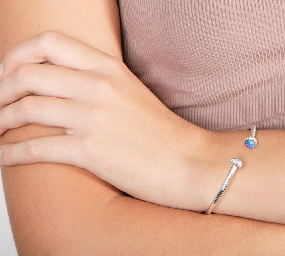 The picture shows a model wearing a 925 sterling silver bangle with two opalite gemstones and topaz.