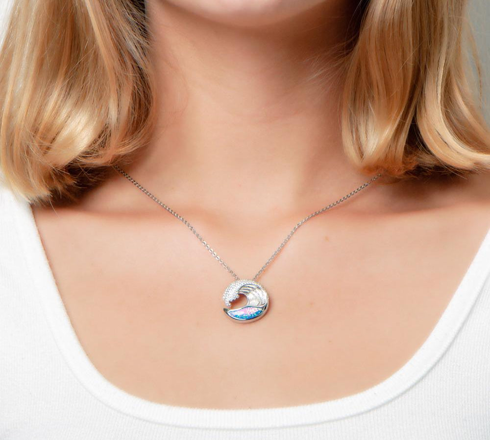 The picture shows a model wearing a 925 sterling silver opalite ocean wave pendant with cubic zirconia.
