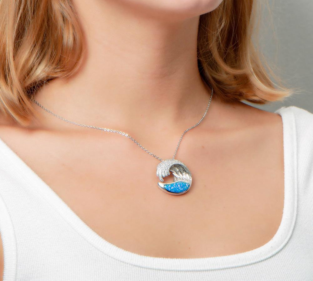 The picture shows a model wearing a 925 sterling silver opalite ocean wave pendant with cubic zirconia.