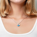 The picture shows a model wearing a 925 sterling silver opalite ocean wave pendant with cubic zirconia.
