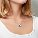 The picture shows a model wearing a 925 sterling silver opalite ocean wave pendant with cubic zirconia.
