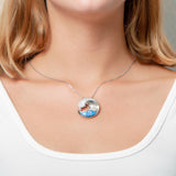 The picture shows a model wearing a 925 sterling silver opalite ocean wave pendant with cubic zirconia.