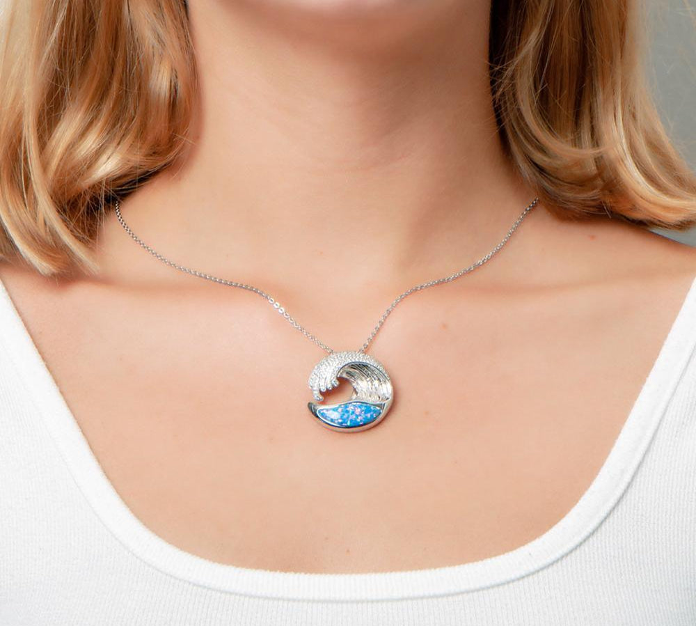 The picture shows a model wearing a 925 sterling silver opalite ocean wave pendant with cubic zirconia.