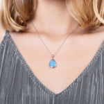 The picture shows a model wearing a 925 sterling silver opalite reuleaux teardrop pendant with cubic zirconia.