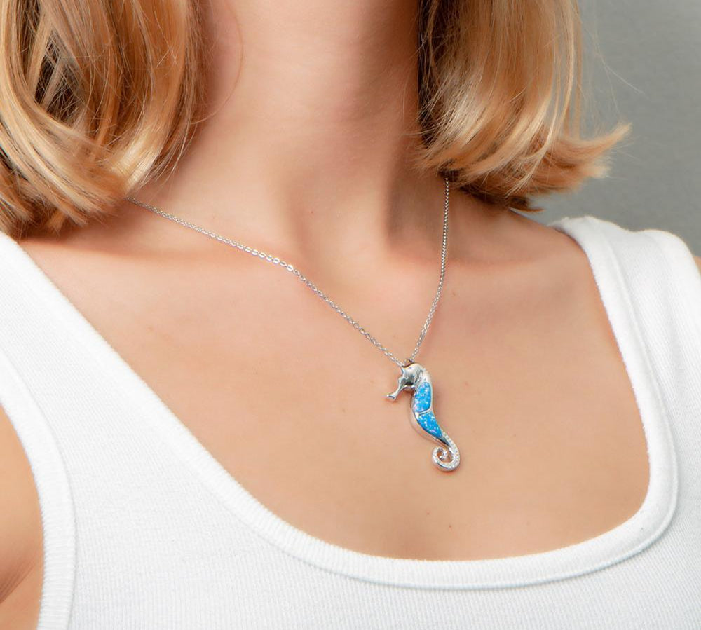 The picture shows a model wearing a 925 sterling silver opalite seahorse pendant with topaz.