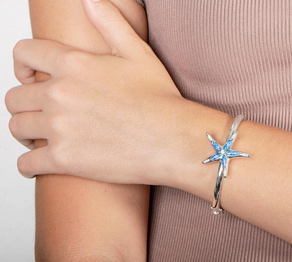 The picture shows a model wearing a 925 sterling silver opalite sea star bangle bangle with topaz.