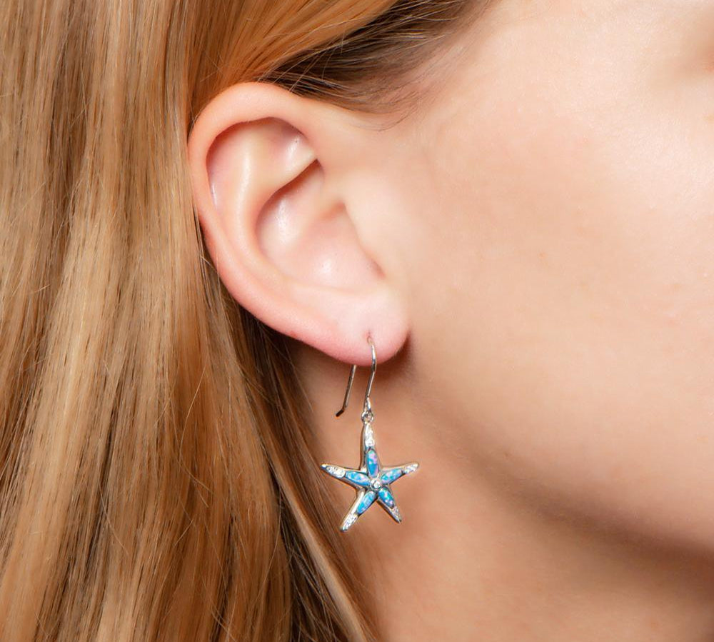 The picture shows a model wearing a 925 sterling silver opalite sea star earring with topaz.
