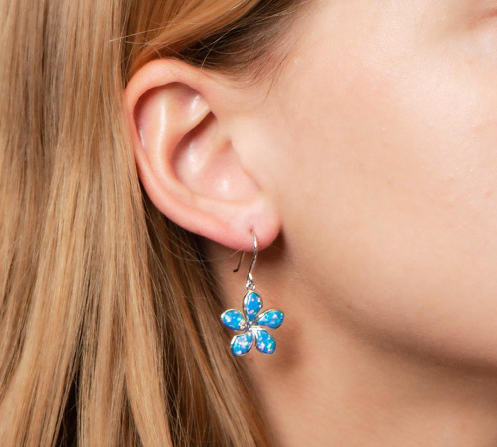 In this photo there is a close-up of a model with strawberry blonde hair wearing sterling silver plumeria hook earrings with blue opalite gemstones.