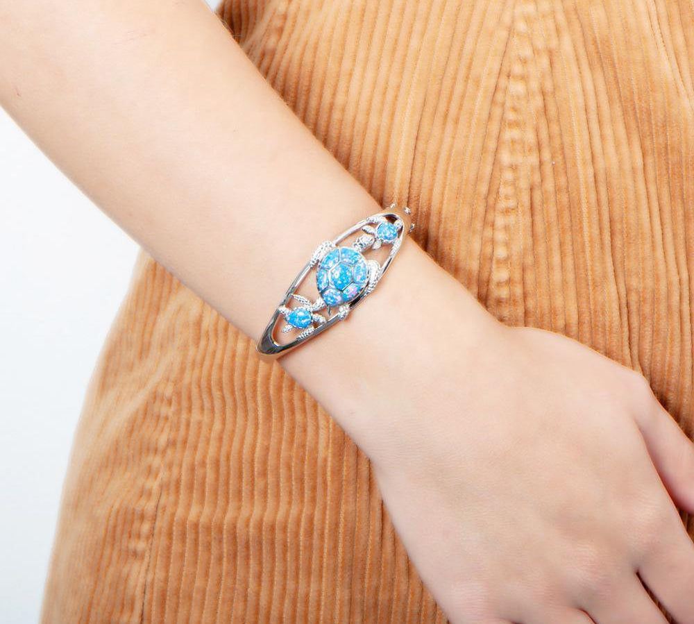 The picture shows a model wearing a 925 sterling silver opalite three sea turtle bangle.