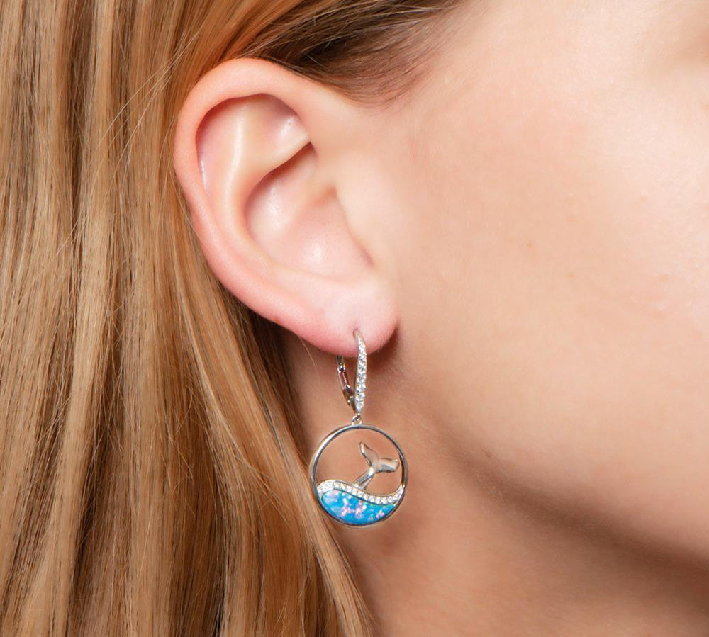 The picture shows a model wearing a 925 sterling silver opalite whale wave earring.